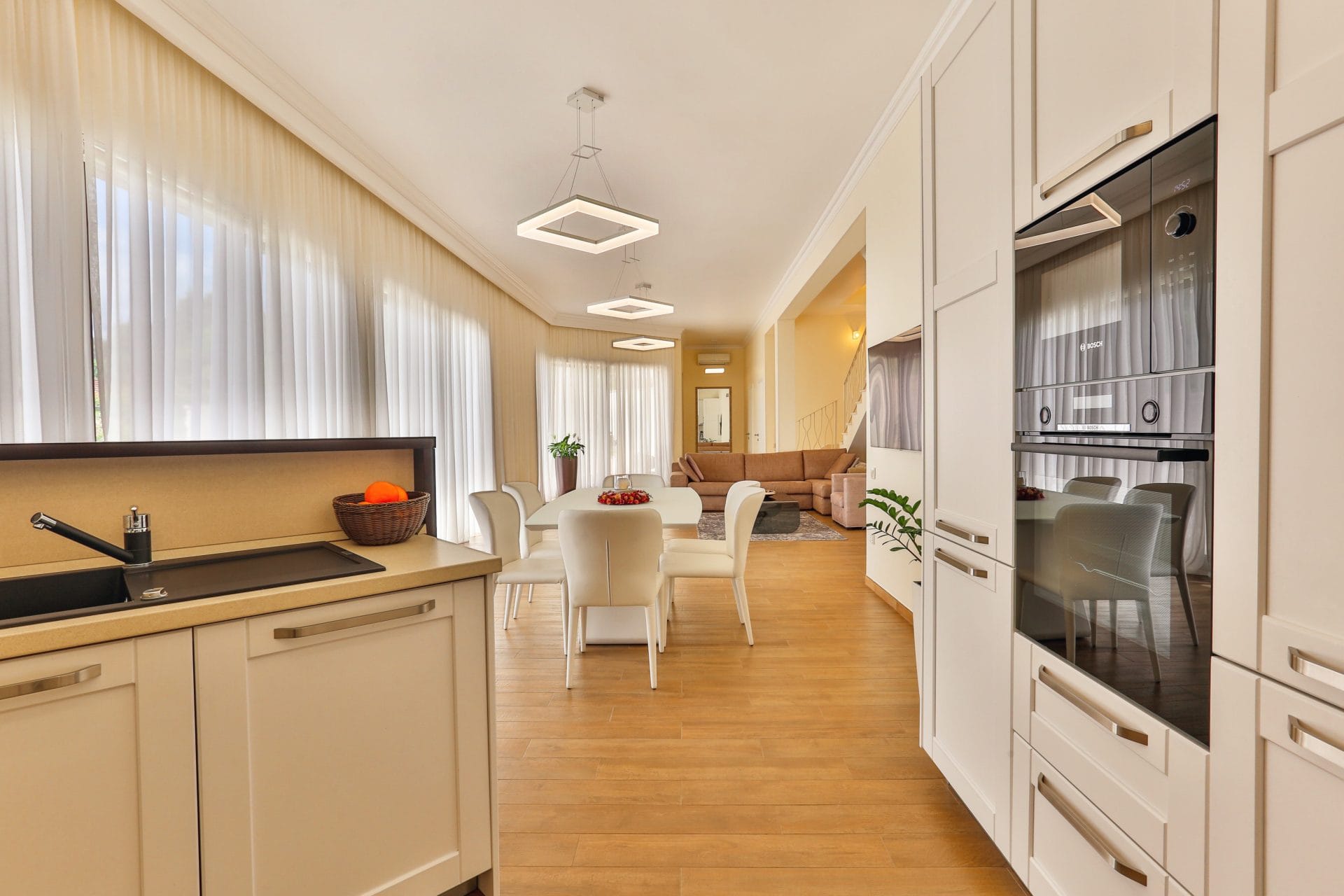 Modern kitchen-living room in a villa in Tivat, Montenegro: light-colored furniture, built-in appliances, and a dining area.