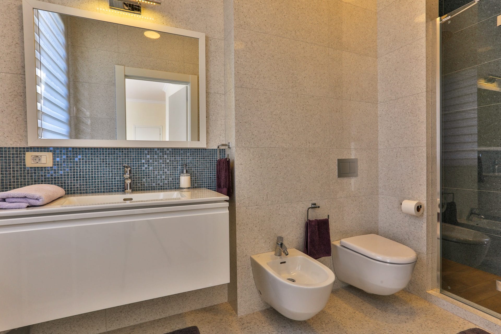 Modern bathroom with a shower cabin and bidet in a villa in Tivat, Montenegro: light tiles and blue mosaic.