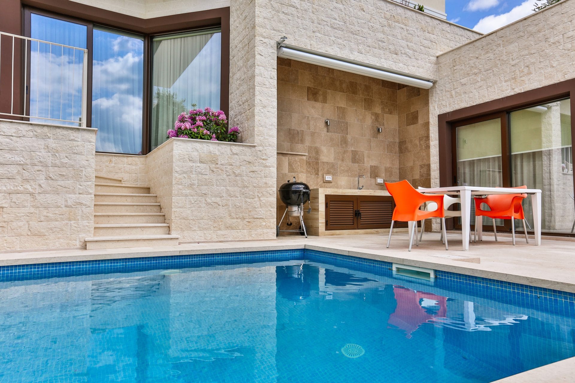 Private pool and terrace with barbecue area at a villa in Tivat, Montenegro: modern stone finish and summer furniture.