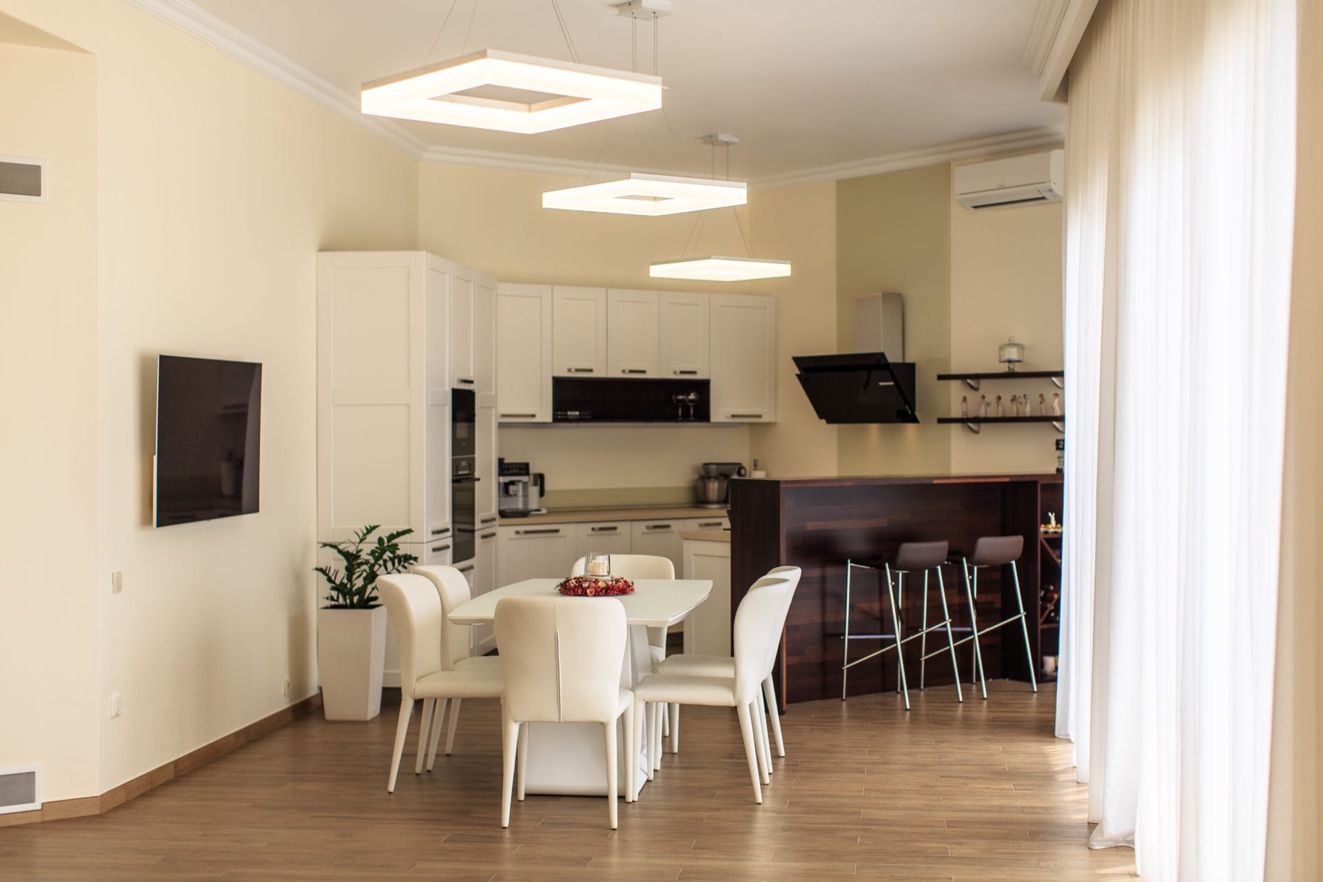 Modern kitchen-dining room with white cabinetry and a breakfast bar in a villa in Tivat, Montenegro.