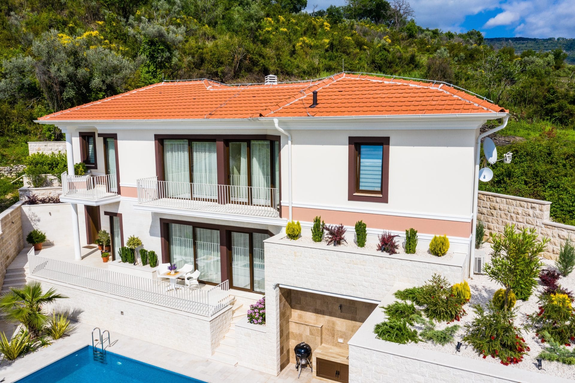 Two-story villa in Tivat, Montenegro: modern facade, terraces, swimming pool, and landscape design against a mountain backdrop.