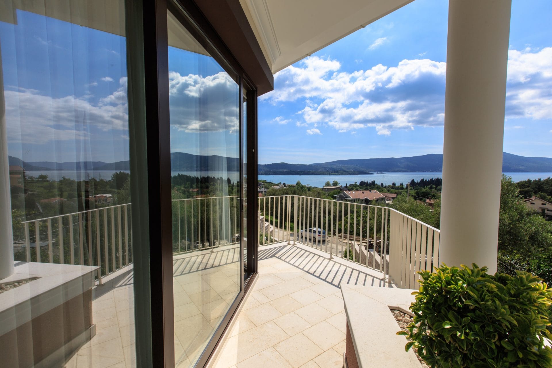 Panoramic balcony of a villa in Tivat, Montenegro, with sea and mountain views and panoramic glazing in a modern style.