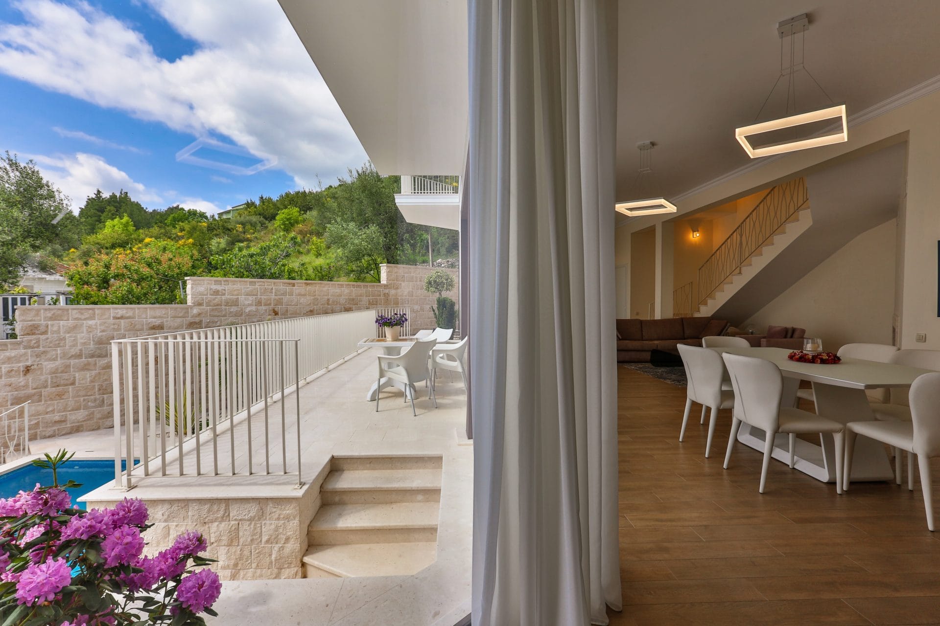 Villa living room in Tivat, Montenegro: access to the terrace with a pool, modern furniture, and panoramic mountain views.