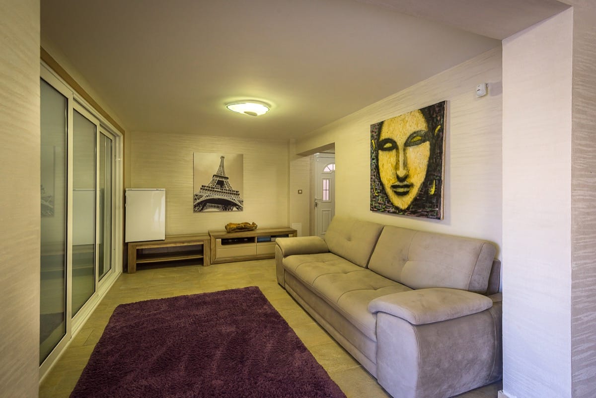 Dnevna soba u vili u Krašićima, Crna Gora: bež sofa, ljubičasti tepih, dekor sa Ajfelovim tornjem i panoramski prozori.