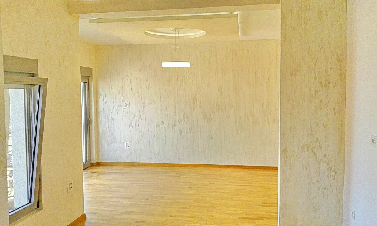 Svetla dnevna soba u stanu u Bečićima, Crna Gora: dekorativni malter, parketni pod i savremeno osvetljenje.