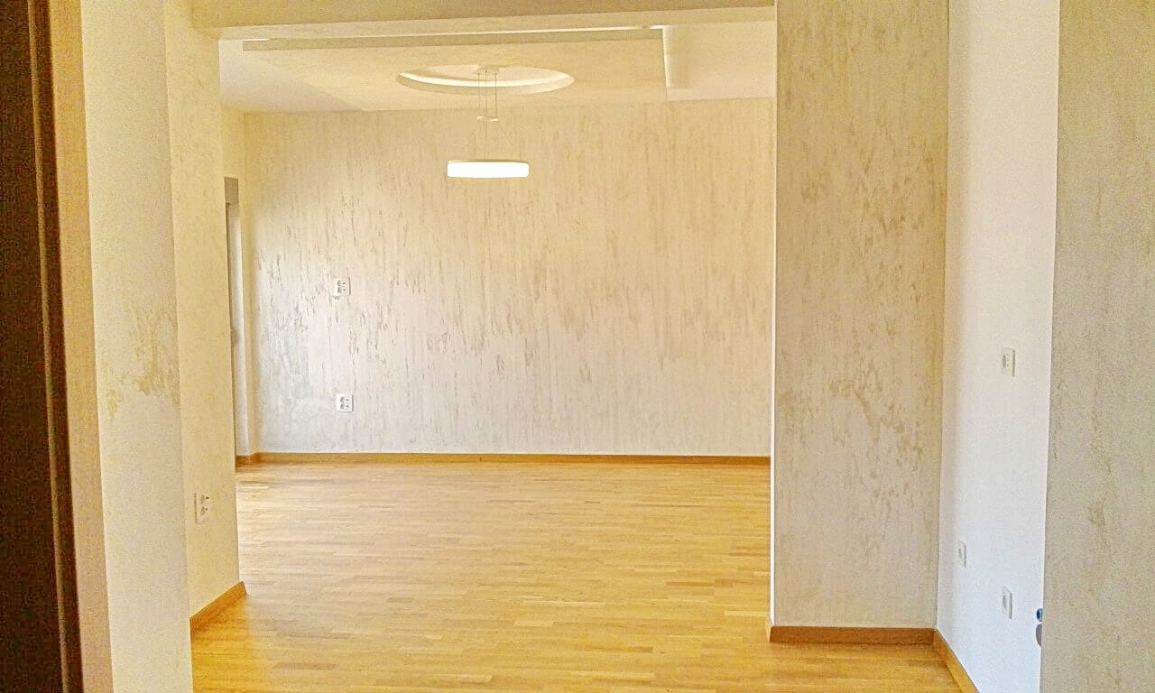 Svetla dnevna soba u stanu u Bečićima, Crna Gora: parketni pod, dekorativni malter i savremeno osvetljenje.