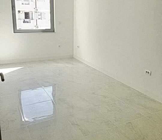 Svetla dnevna soba sa završnom obradom od porcelanskog kamena u novom stambenom kompleksu u Budvi, Crna Gora.