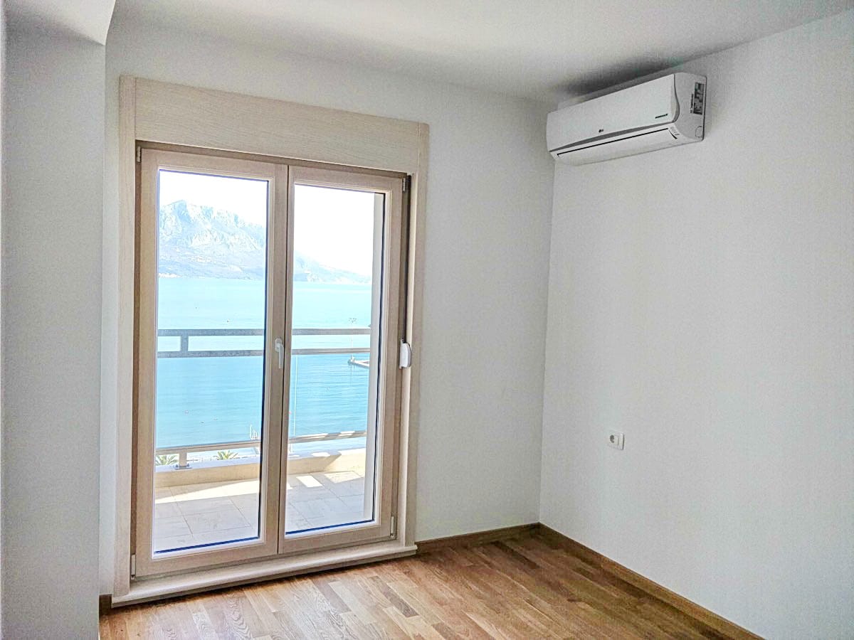 Spavaća soba u stanu u Budvi, Crna Gora: svetla obrada, klima-uređaj, panoramski pogled na more i planine sa balkona.