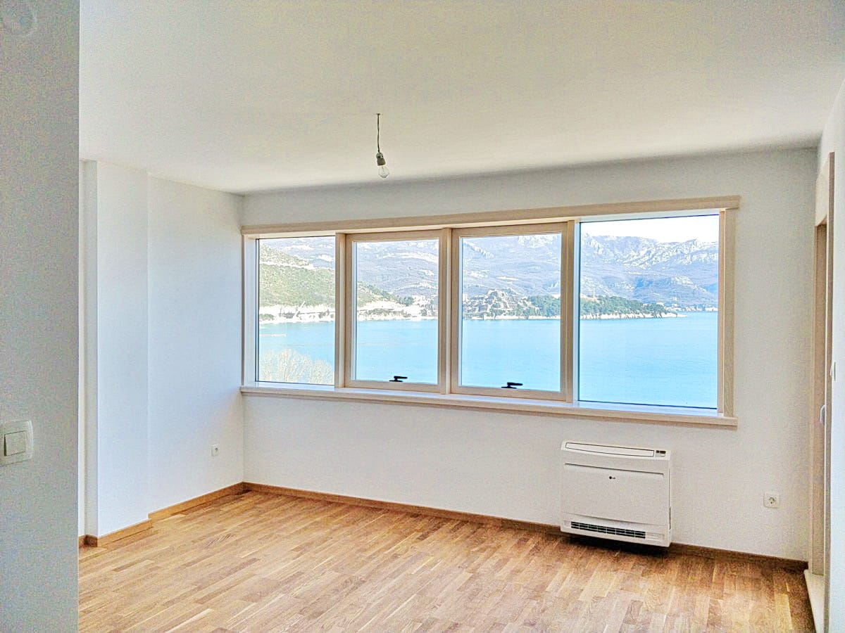 Svetla dnevna soba u Budvi, Crna Gora, sa panoramskim pogledom na more i planine, parketnim podom i klima-uređajem.