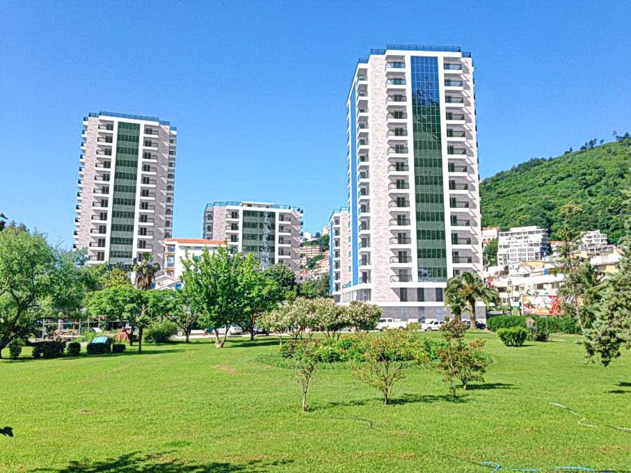 Savremeni stambeni kompleksi sa panoramskim prozorima i zelenim parkom u Budvi, Crna Gora. Pogled na elitne novogradnje.
