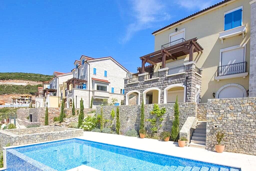 Savremene vile sa bazenom i kamenim oblogama fasada u Luštici, Crna Gora: pogled na stambeni kompleks spolja.