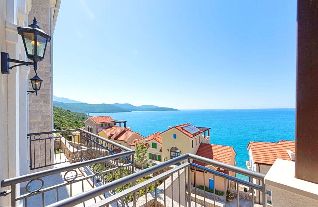 Pogled sa balkona stana u Luštici, Crna Gora: panorama Jadranskog mora, mediteranske vile i planine.