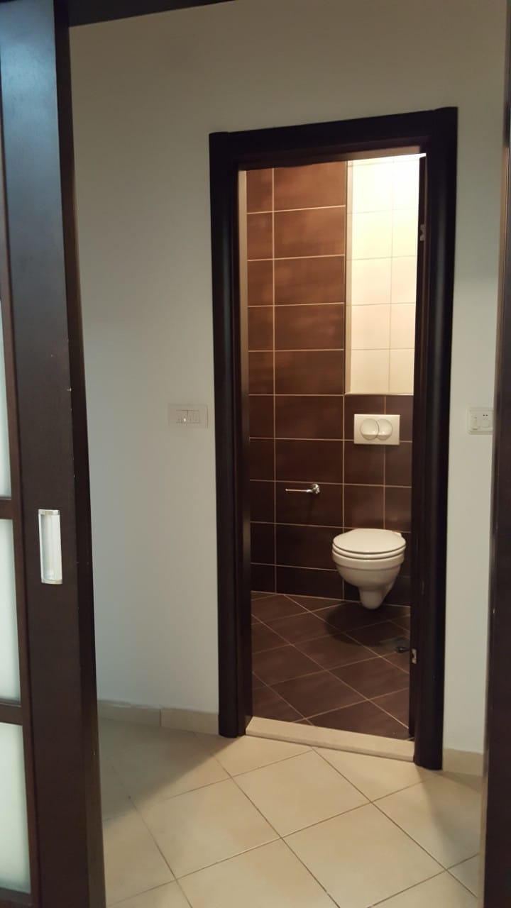Savremeno kupatilo sa braon pločicama i visećom WC šoljom u stanu, grad Budva, Crna Gora.