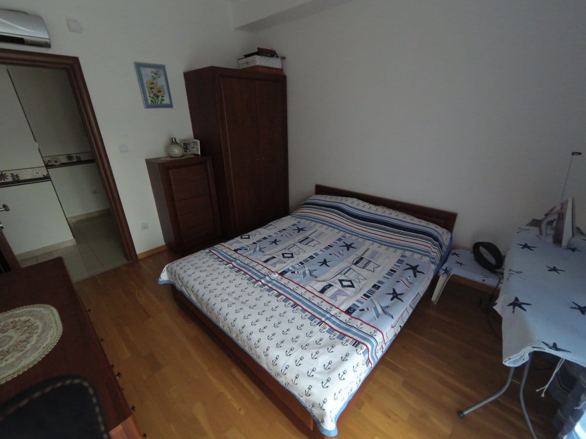 Bedroom with a double bed and wooden furniture in an apartment for sale, Budva, Montenegro.