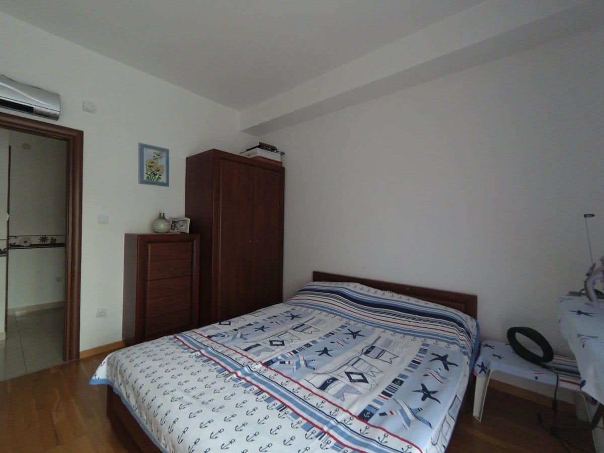 Bedroom with a double bed and a wooden wardrobe in an apartment in Budva, Montenegro. Light finishes, parquet flooring.