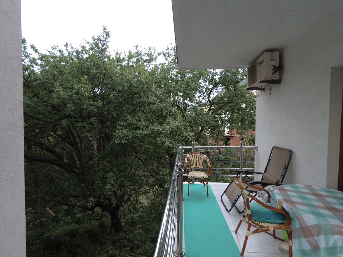 Cozy balcony with garden furniture and a view of greenery in an apartment in Budva, Montenegro. Flooring, air conditioner.