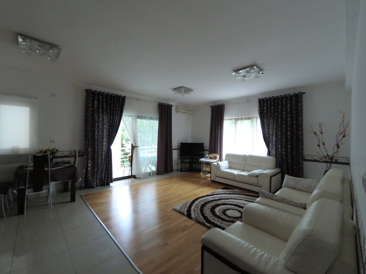 Spacious living room with white leather sofas and access to the terrace in an apartment, Budva, Montenegro.