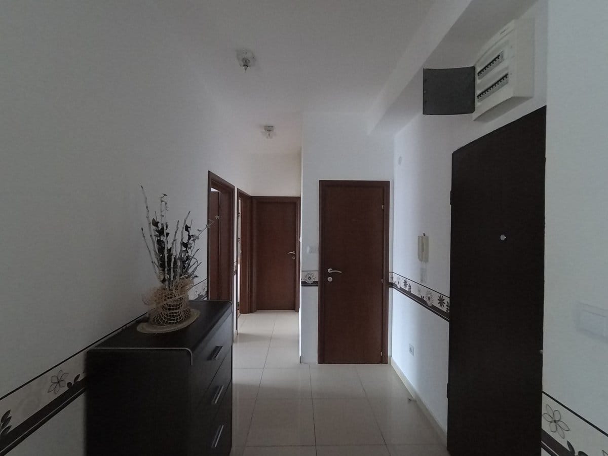 Bright hallway in an apartment in Budva, Montenegro: tiled floor, dark interior doors, and a dresser in the interior.