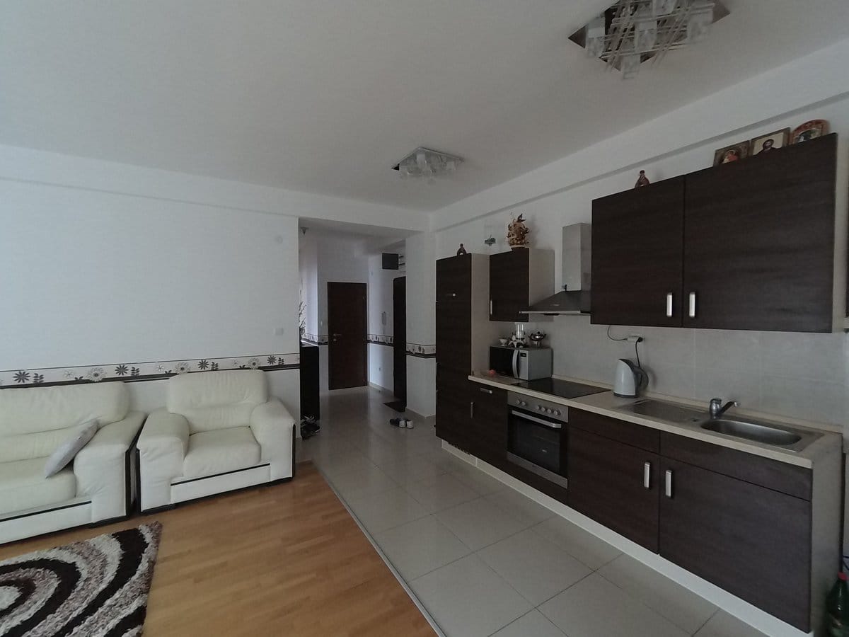 Kitchen-living room with dark cabinetry and a white leather sofa in an apartment in Budva, Montenegro.
