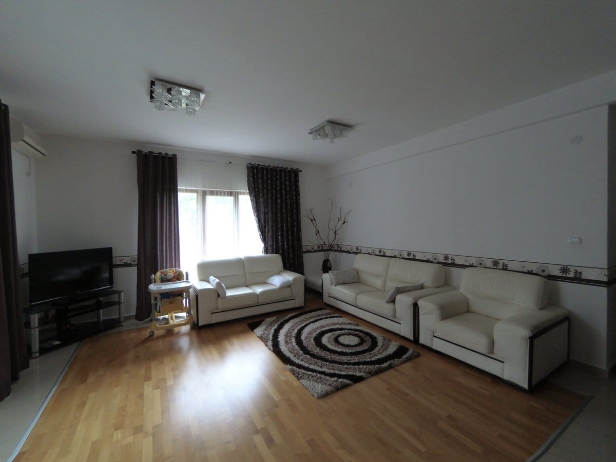 Spacious living room with white leather furniture and parquet flooring in an apartment for sale, Budva, Montenegro.