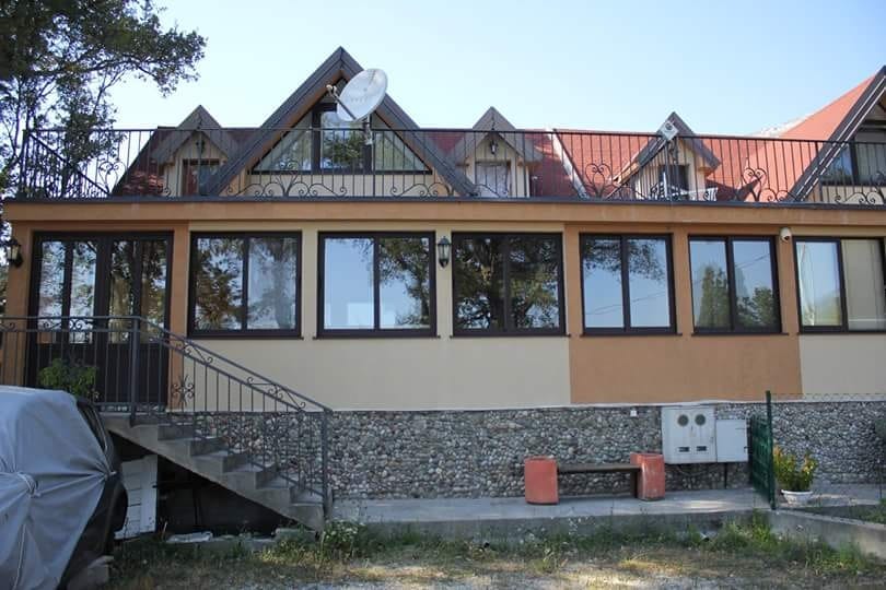 Dvospratna kuća u Sutomoru, Crna Gora: fasada sa kamenim oblogama, panoramskim prozorima i terasom sa kovanom ogradom.
