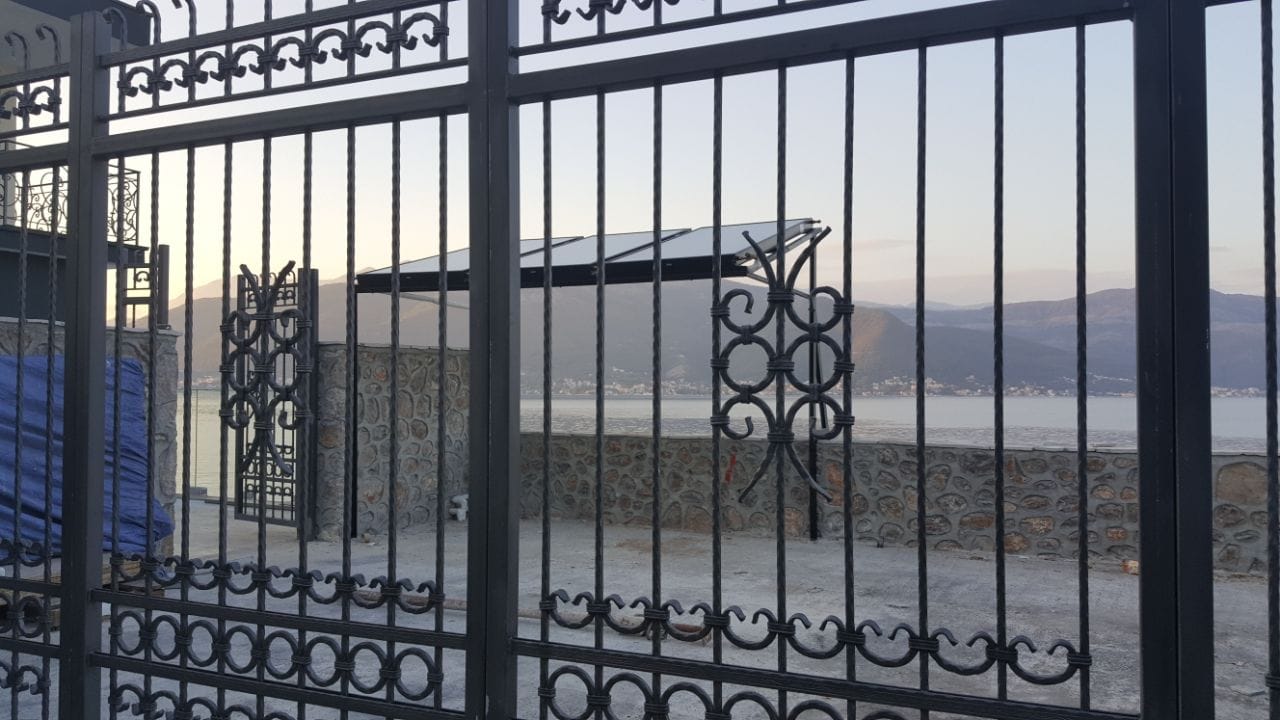 Kovana kapija vile u Krašićima, Crna Gora, s pogledom na more i planine, terasa sa kamenim oblogama i nadstrešnicom.
