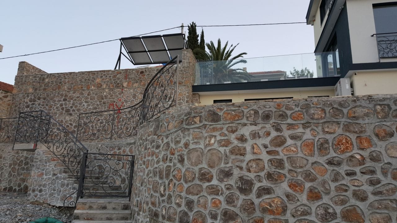 Vila u Krašićima, Crna Gora: kamena fasadna obloga, kovano stepenište i terasa sa staklenom ogradom.