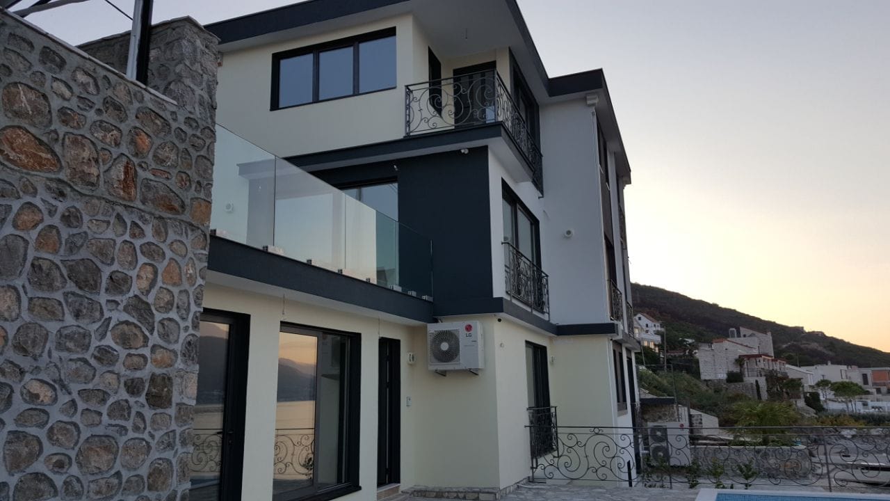 Savremena trospratna vila u Krašićima, Crna Gora: fasada sa kamenim oblogama, balkonima i panoramskim prozorima.