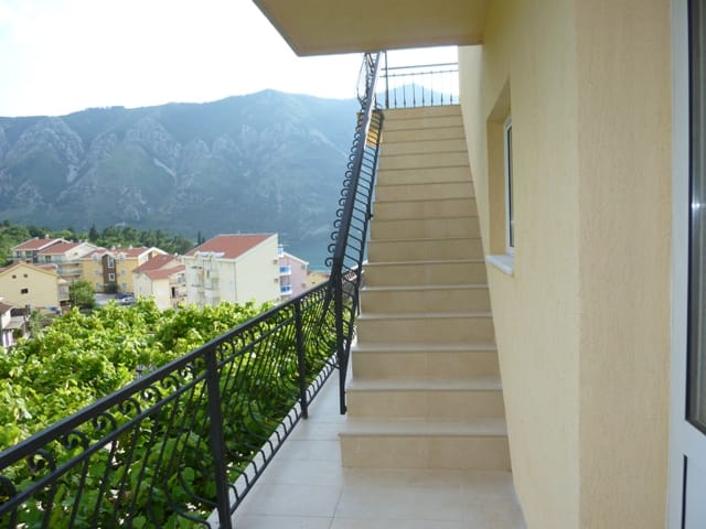Balkon vile u Dobroti, Crna Gora: kameno stepenište, kovane ograde i panoramski pogled na planine i Bokokotorski zaliv.