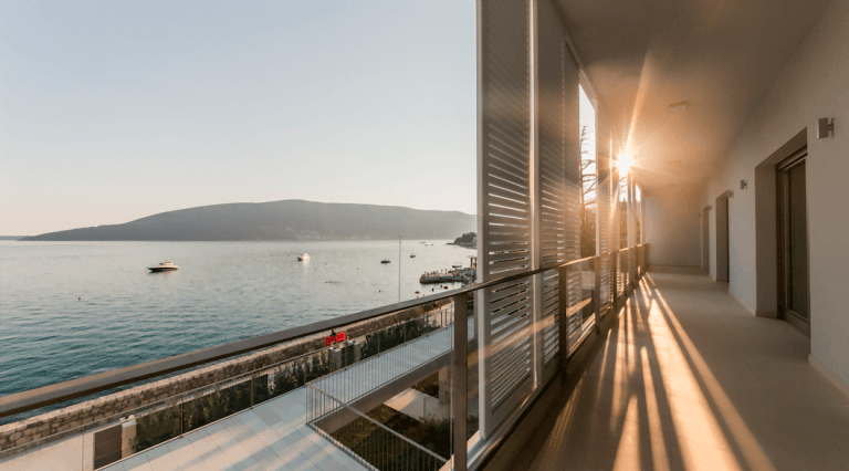 Przestronny balkon willi w Herceg Novi, Czarnogóra, z panoramicznym widokiem na morze, jachty i światło zachodzącego słońca.
