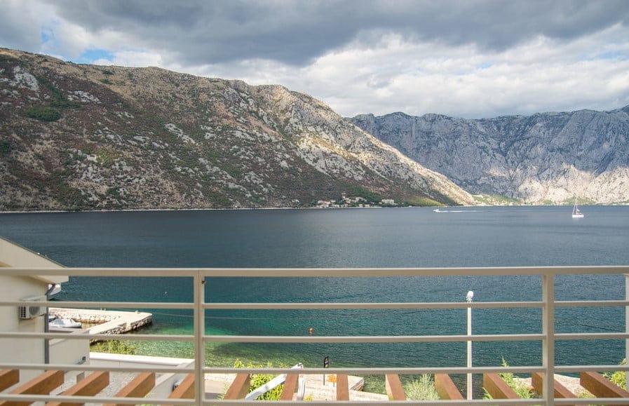 Widok z balkonu willi w Stolivie, Czarnogóra: panorama Zatoki Kotorskiej, gór i wybrzeża morskiego.