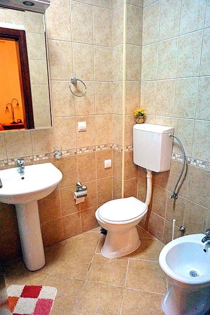 Bathroom in an apartment in Stoliv, Montenegro: white sanitary ware, bidet, and beige tiles in a classic style.