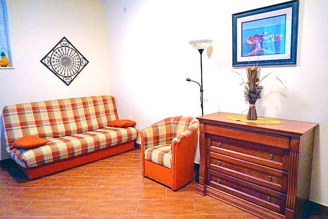 Cozy living room with a checkered sofa and a dresser in an apartment, the town of Stoliv, Montenegro. Interior with tiled flooring.