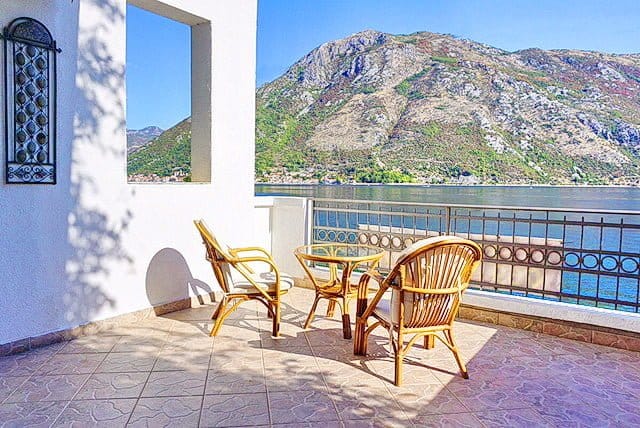 Terrace with wicker furniture and panoramic views of the Bay of Kotor and the mountains, apartment in Stoliv, Montenegro.