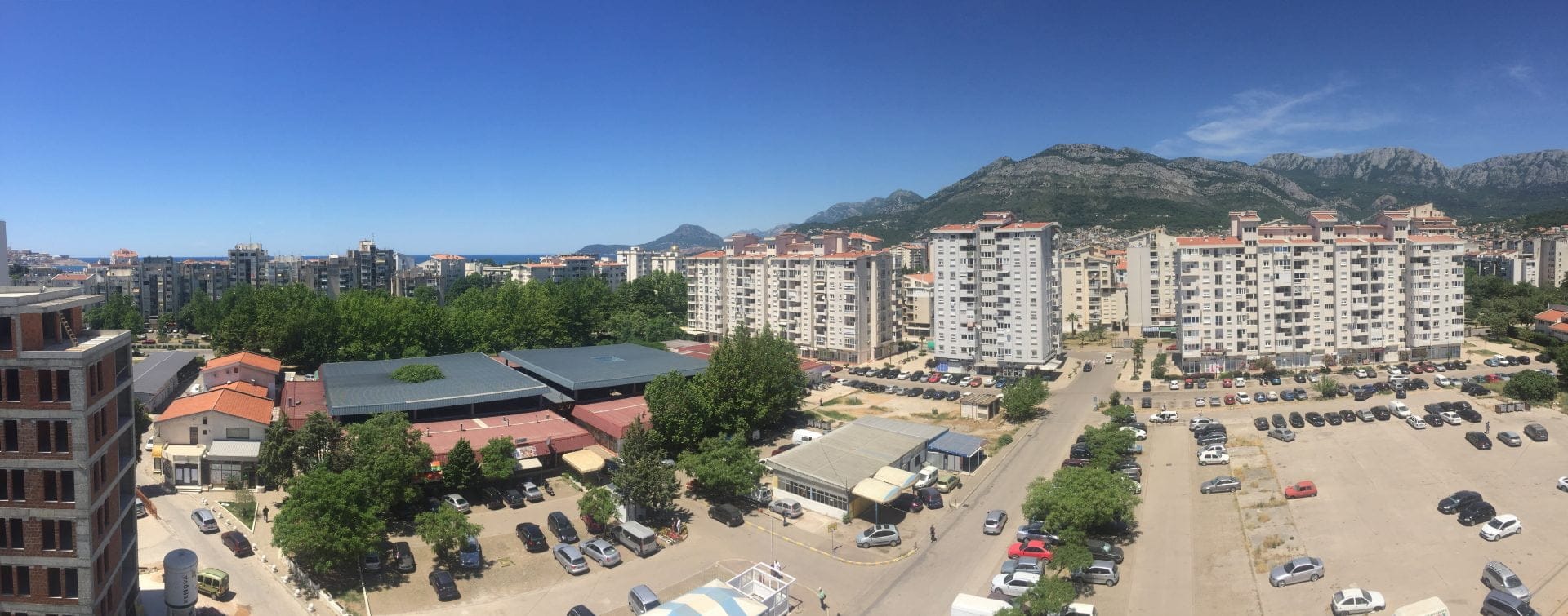 Panoramablick auf die Stadt Bar, Montenegro: Wohnhäuser, Parkplatz und Berglandschaft aus dem Fenster der Wohnung Nr. 1595.