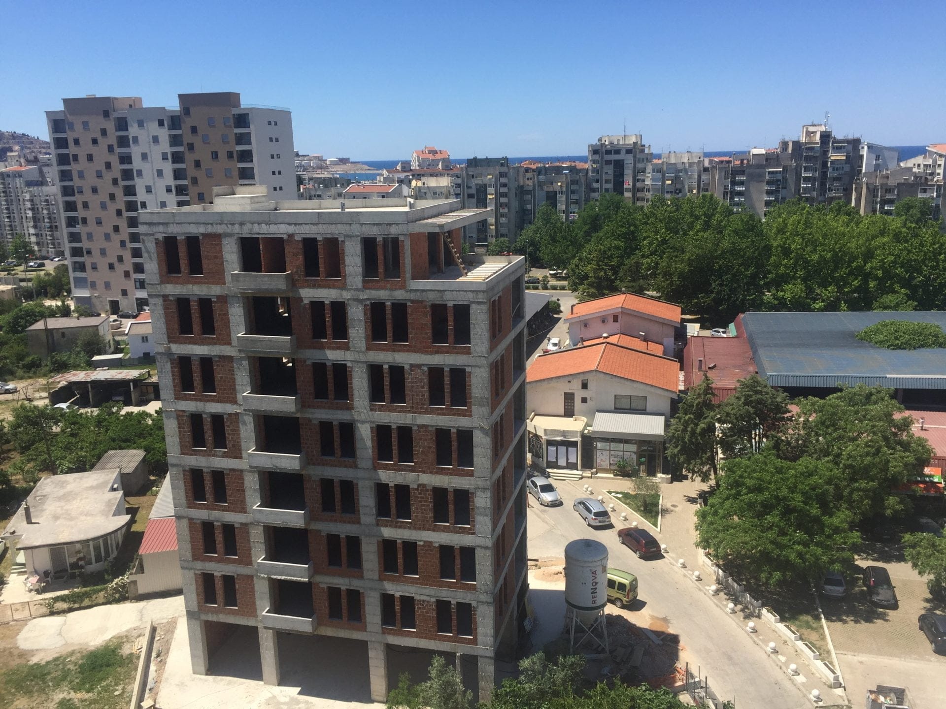 Im Bau befindliches mehrstöckiges Wohngebäude in der Stadt Bar, Montenegro: Blick auf das Immobilienobjekt und die städtische Bebauung aus der Höhe.