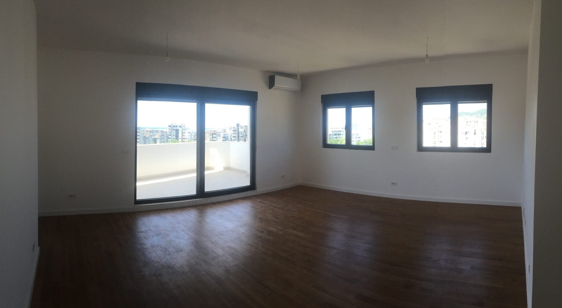 Geräumiges Wohnzimmer mit Parkett, Panoramafenstern und Zugang zur Terrasse in einer Wohnung, Stadt Bar, Montenegro.