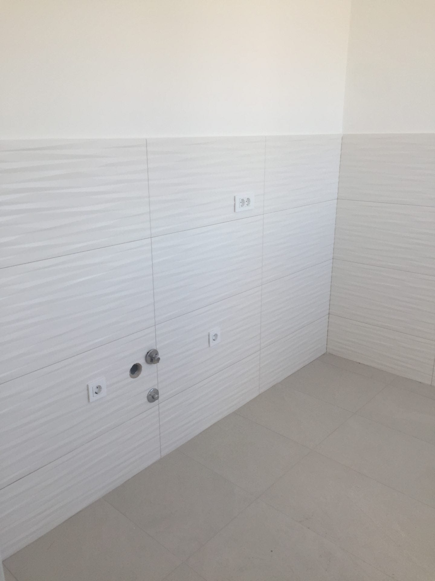 Moderne Küchenausstattung mit heller, strukturierter Fliese in einer neuen Wohnung in Bar, Montenegro.