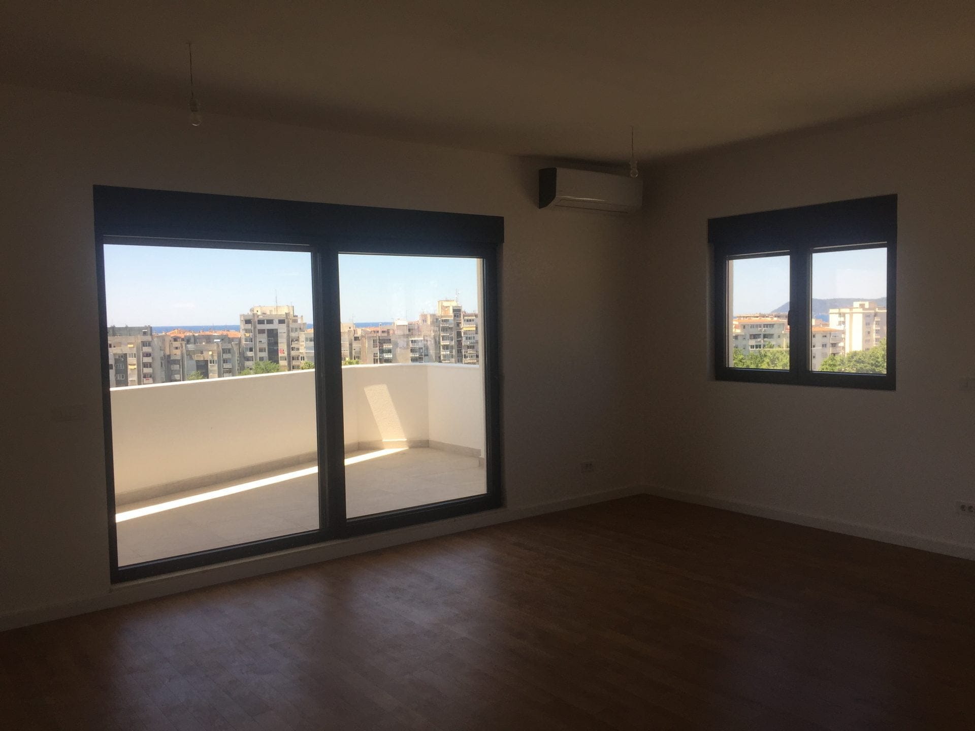 Helles Wohnzimmer mit Panoramablick auf die Terrasse und Meerblick in einer Wohnung in der Stadt Bar, Montenegro.