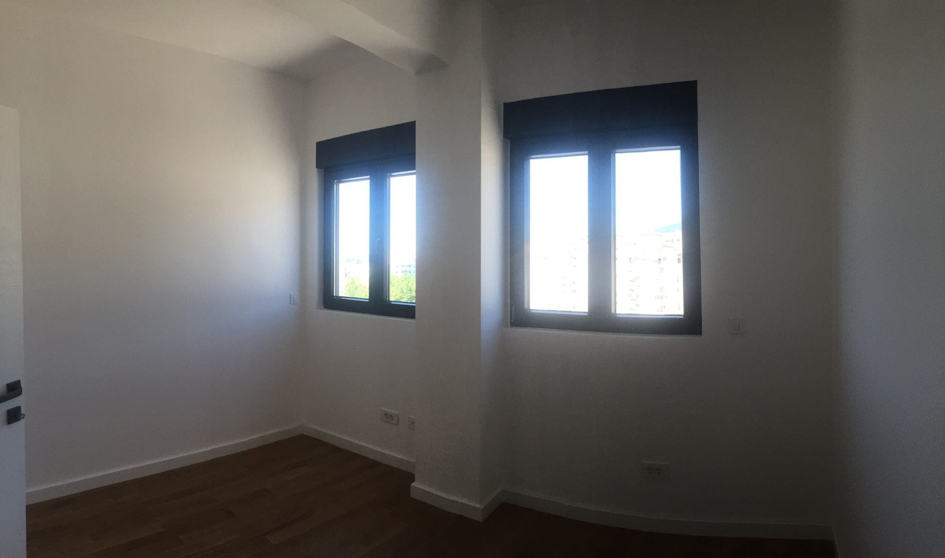Helles Schlafzimmer mit Parkettboden und großen Fenstern in einer Wohnung in der Stadt Bar, Montenegro.