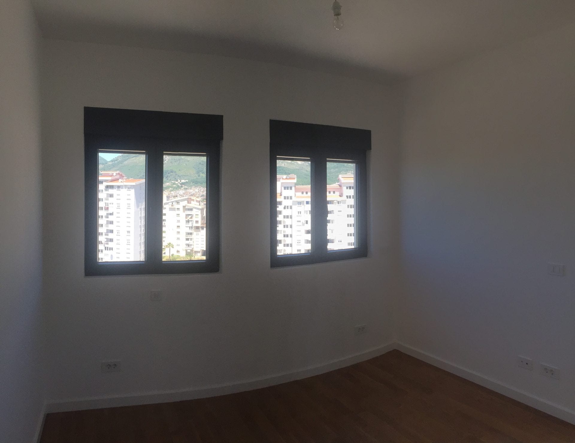 Helles Schlafzimmer mit Parkett und Bergblick in einer neuen Wohnung in der Stadt Bar, Montenegro.