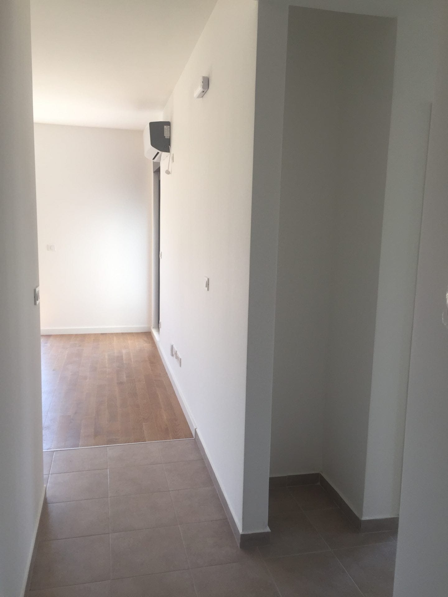 Heller Flur in einer Wohnung in Bar, Montenegro: Fliesenboden, Laminat, weiße Wände und eine installierte Klimaanlage.