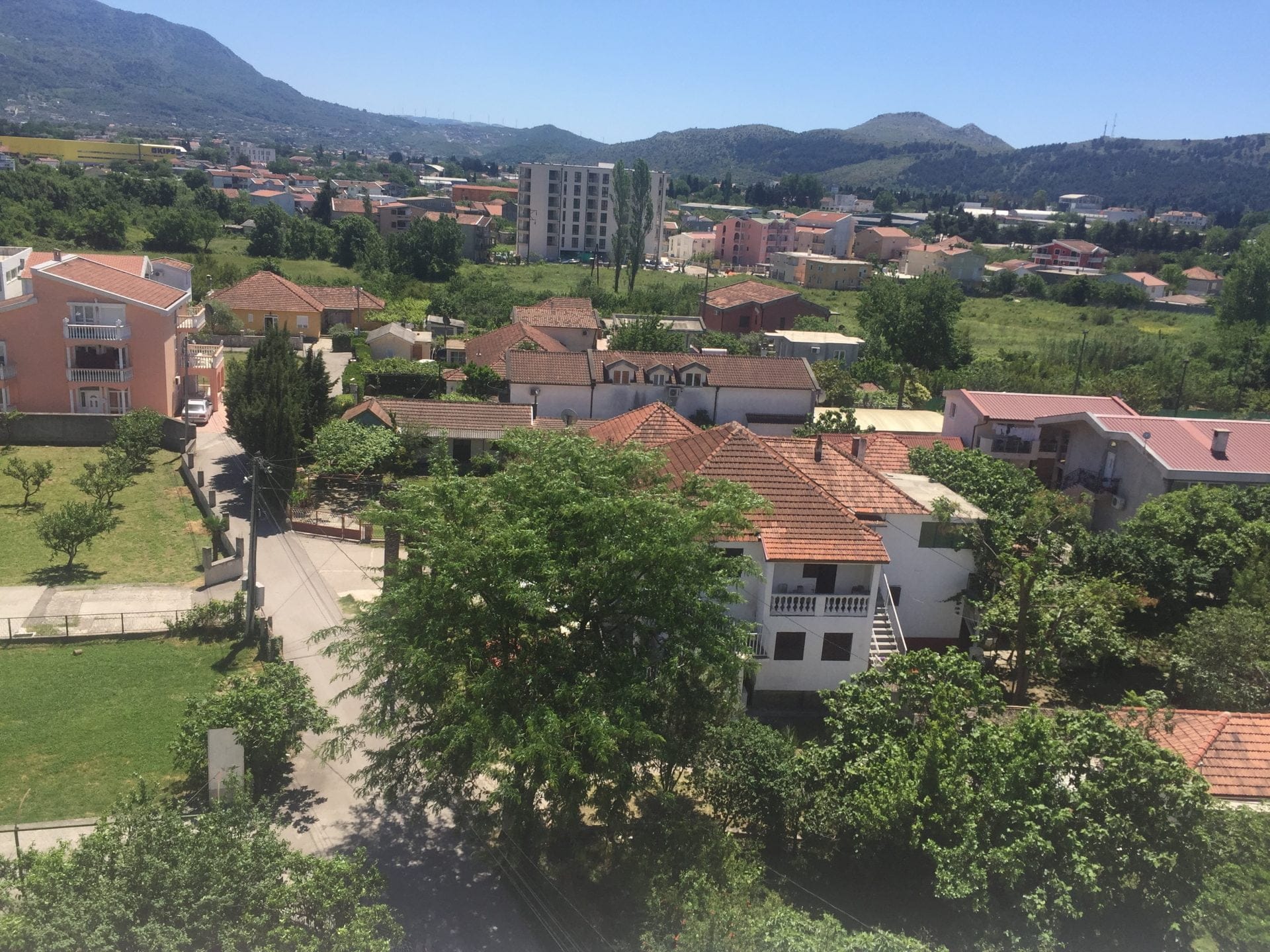 Panoramablick auf die Stadt Bar, Montenegro: Wohngebiet mit Häusern, Ziegeldächern, grünen Bäumen und Bergen.