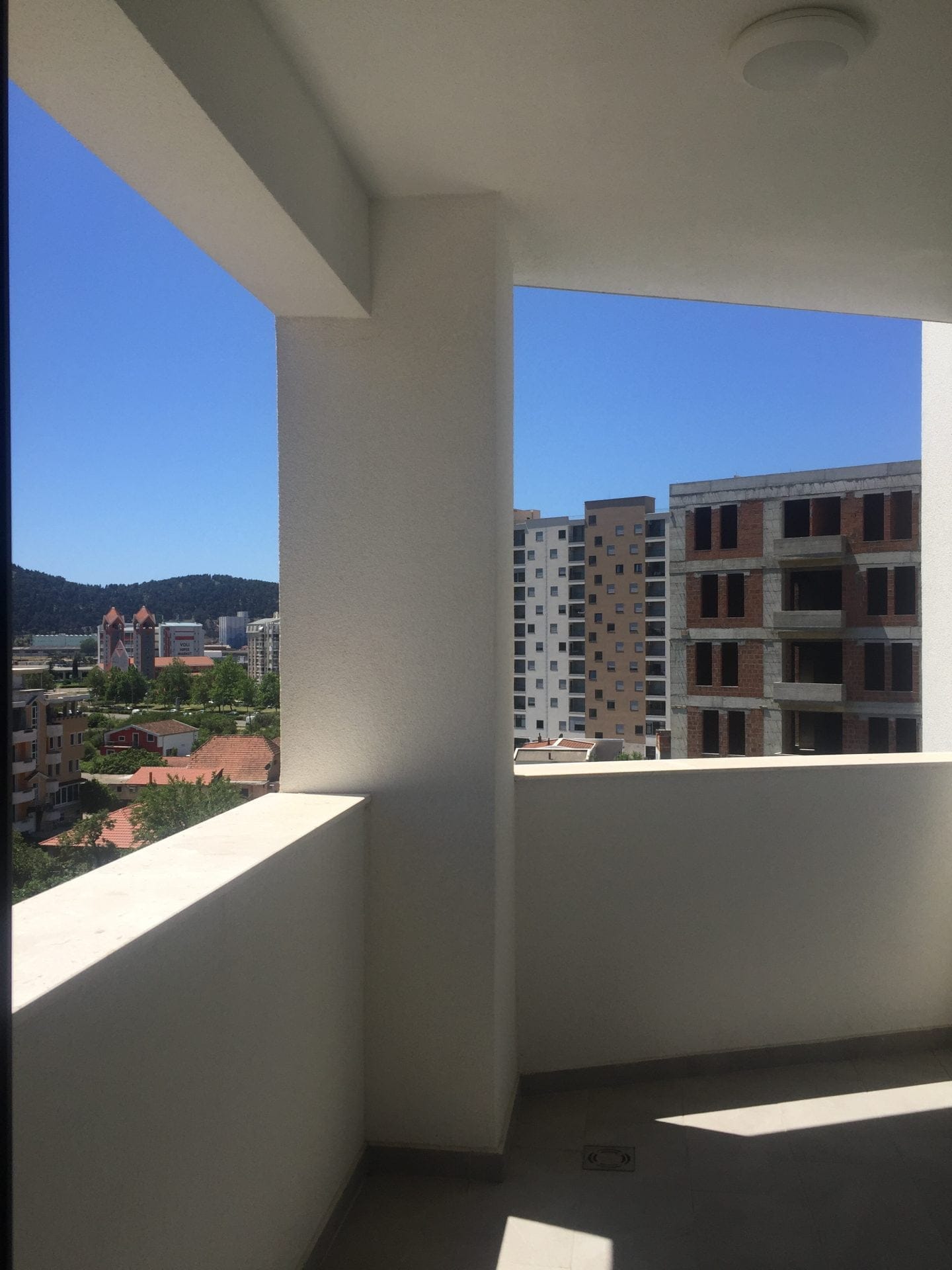Blick vom Balkon einer modernen Wohnung in der Stadt Bar, Montenegro: Panorama der Stadt, Berge und benachbarte Wohnhäuser.