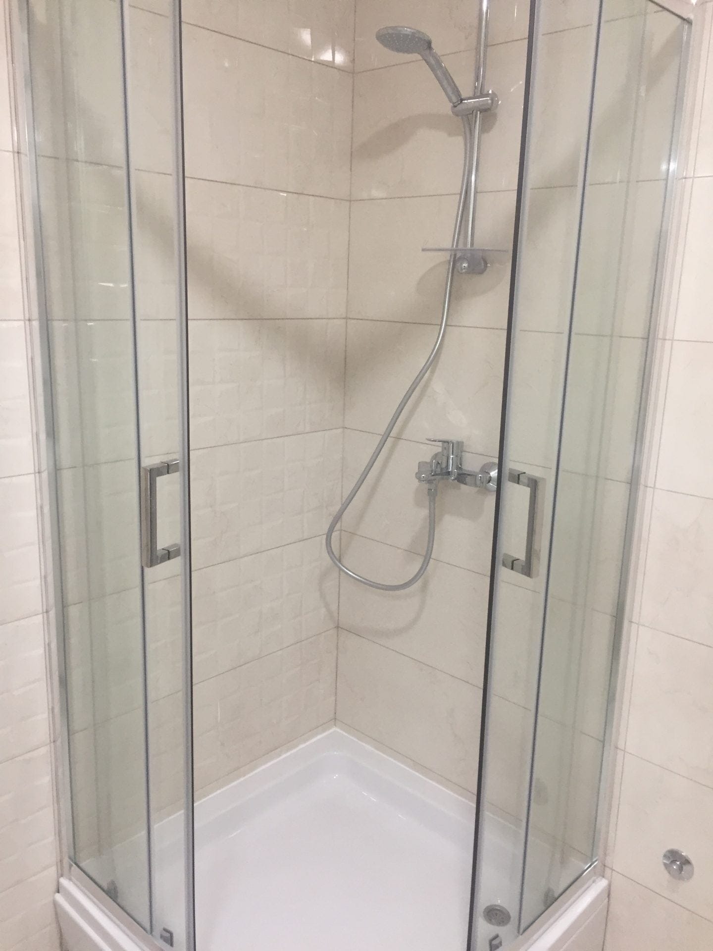 Moderne Duschkabine mit beigen Fliesen im Badezimmer einer Wohnung in Bar, Montenegro.