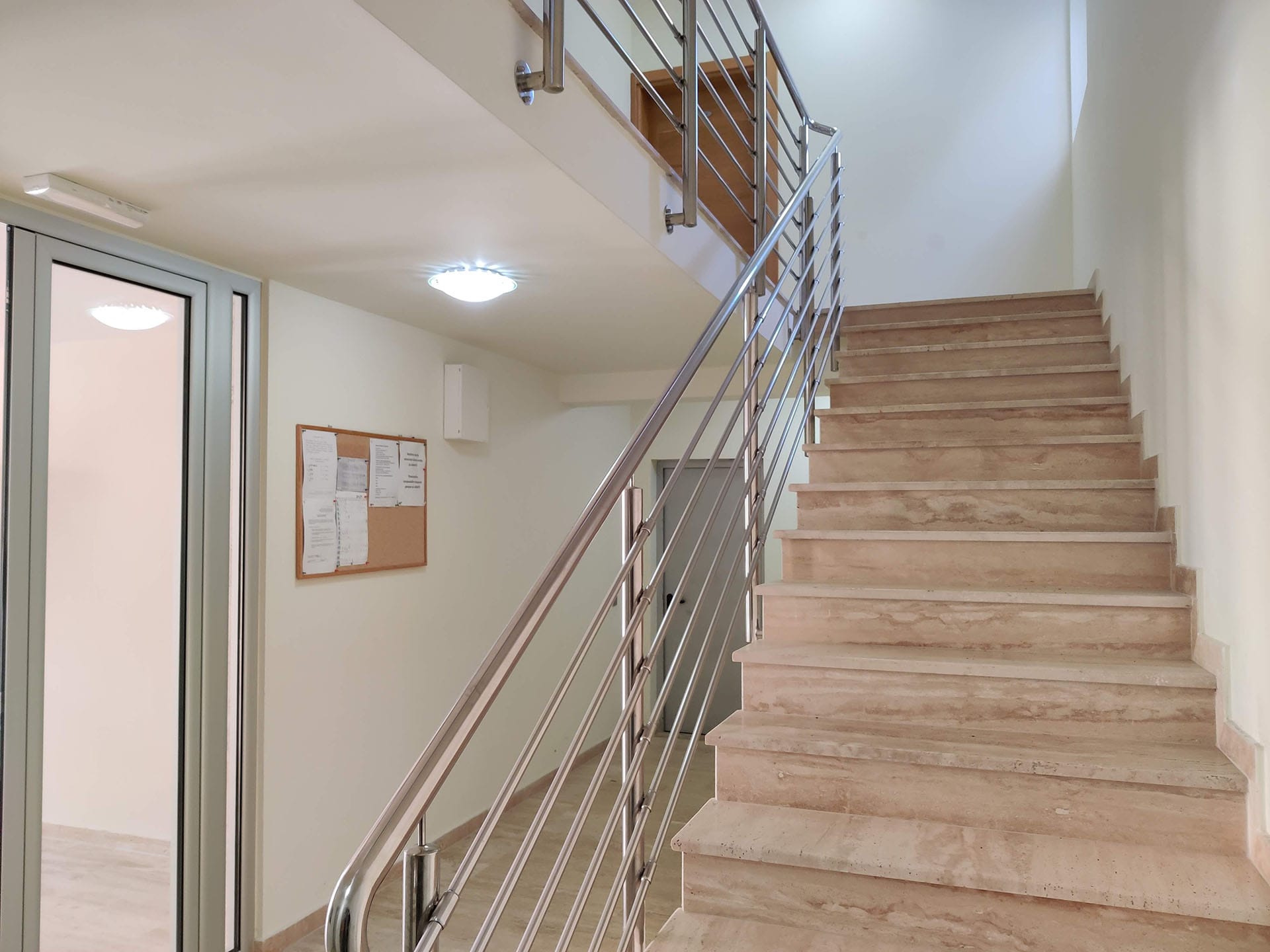 Escalier avec marches en marbre et rampes métalliques dans l’entrée d’un complexe résidentiel à Bečići, Monténégro.