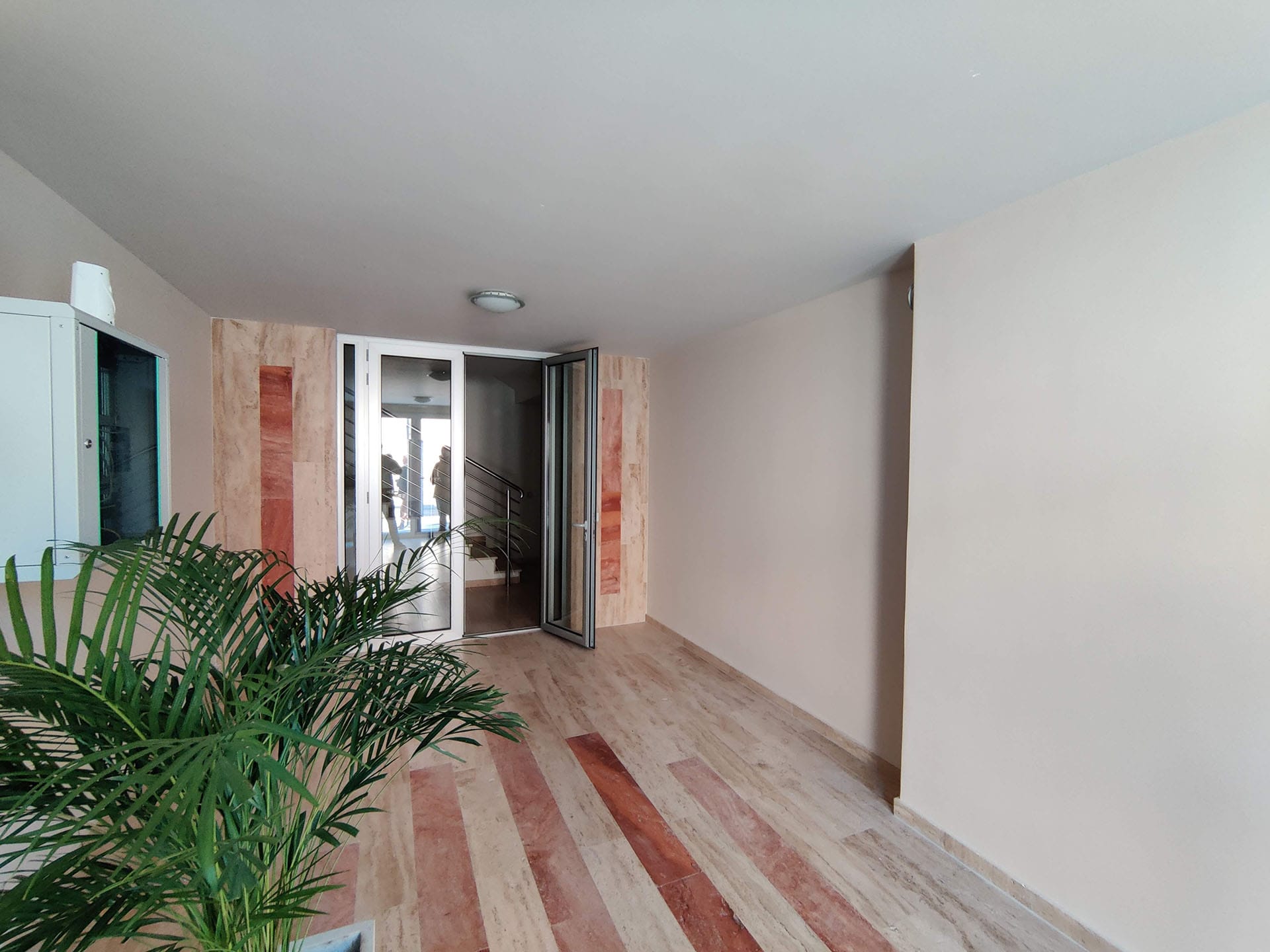Hall lumineux avec finition en pierre et plante vivante dans un complexe résidentiel à Bečići, Monténégro.