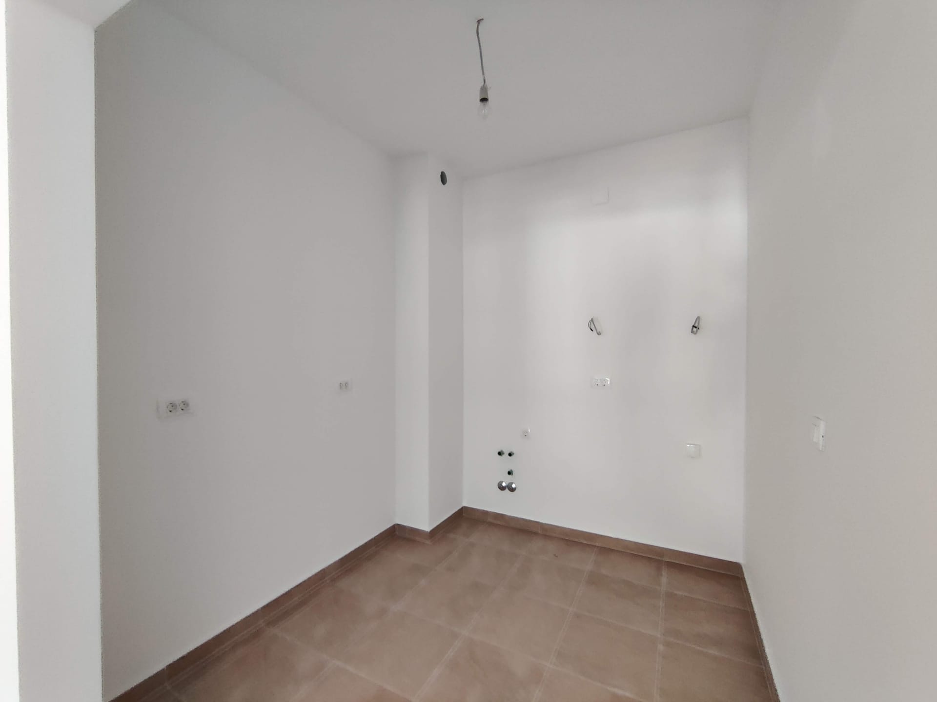 Cuisine vide avec finition blanche et arrivées de réseaux dans un nouvel appartement, Bečići, Monténégro.