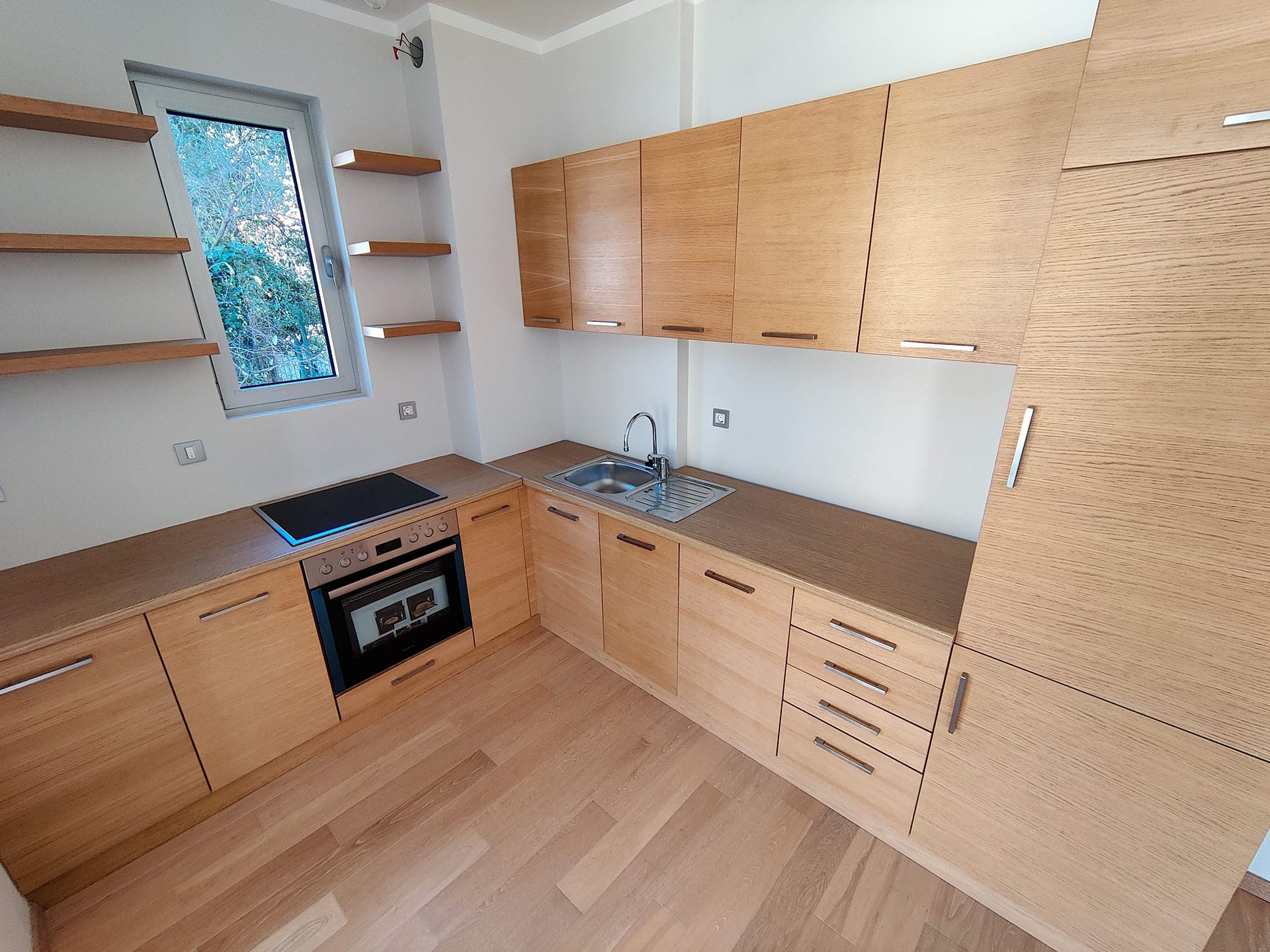 Cuisine moderne avec façades en bois et appareils électroménagers intégrés dans un appartement, Bečići, Monténégro.