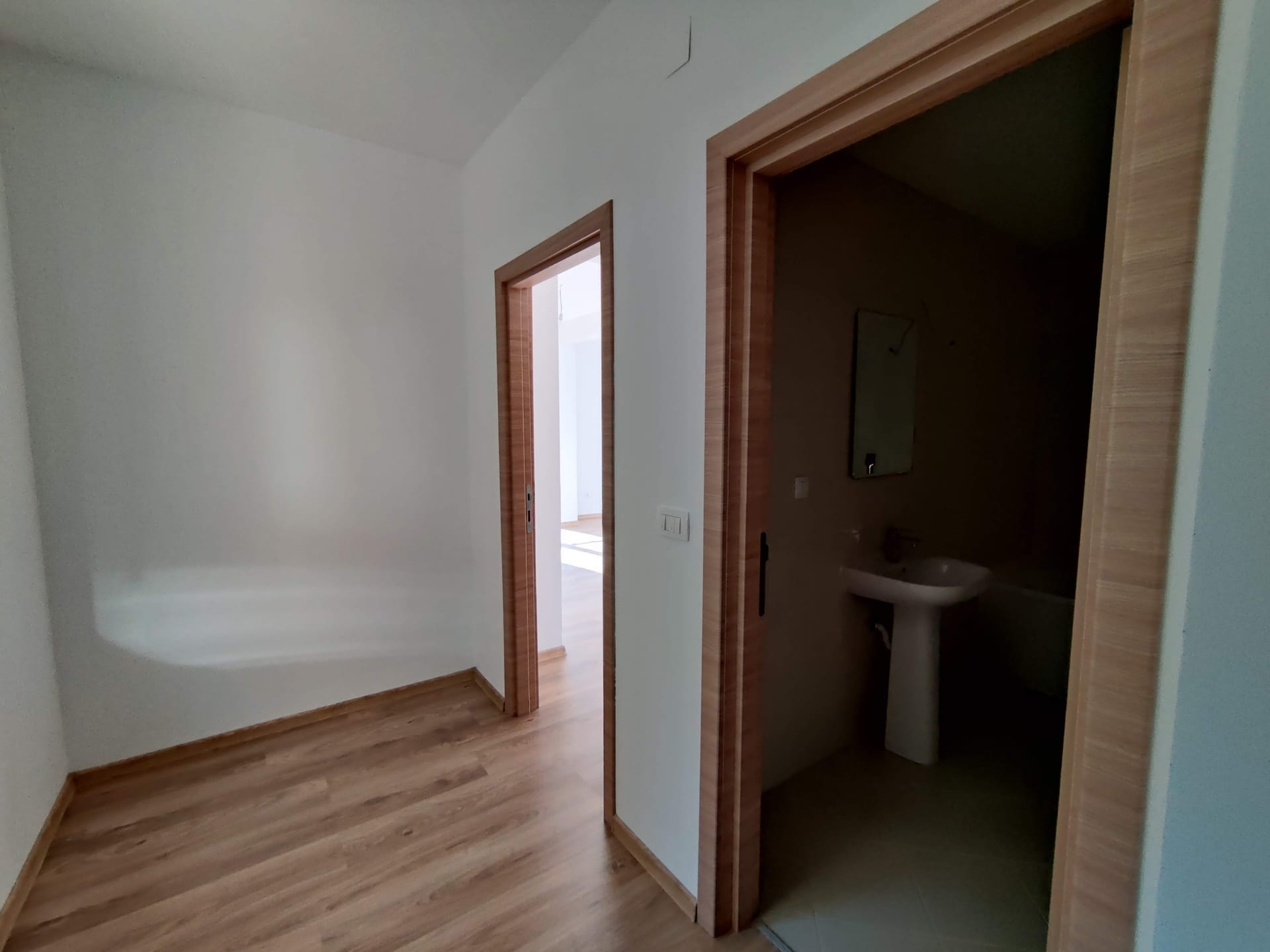 Couloir lumineux avec parquet stratifié et entrée de la salle de bain dans un appartement, Bečići, Monténégro.